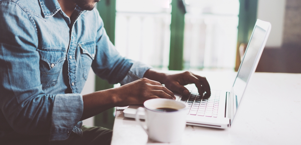 Man Sitting at Laptop with Coffee